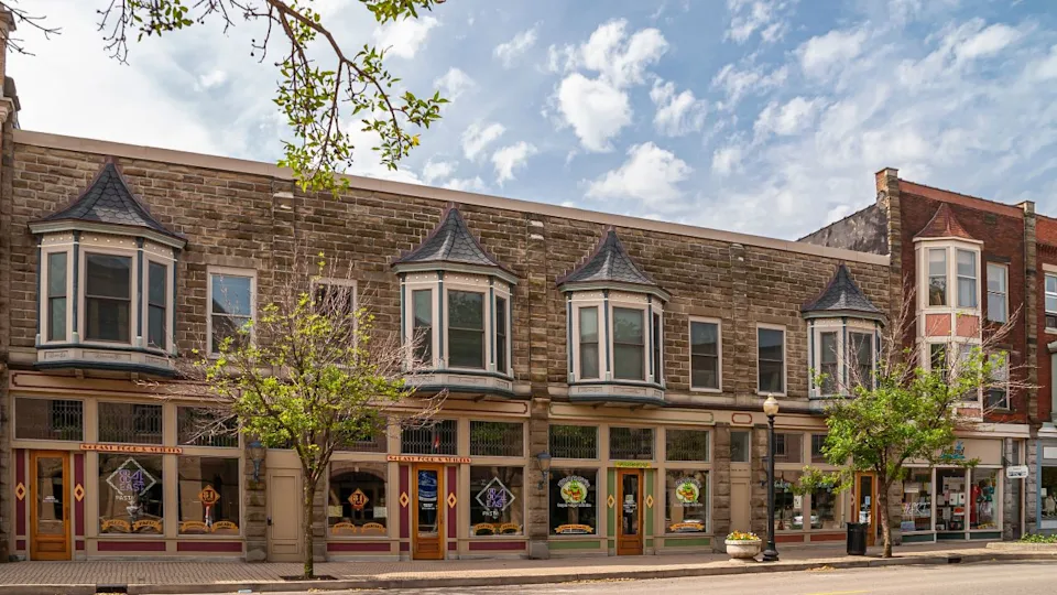 Holland, MI, USA - June 8, 2008: Low long bulding forms row of bars and restaurants downtown under blue cloudscape. Green foliage.