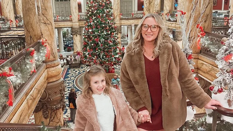 A mother and daughter pose atop the staircase at the Jefferson Hotel at Christmastime.
