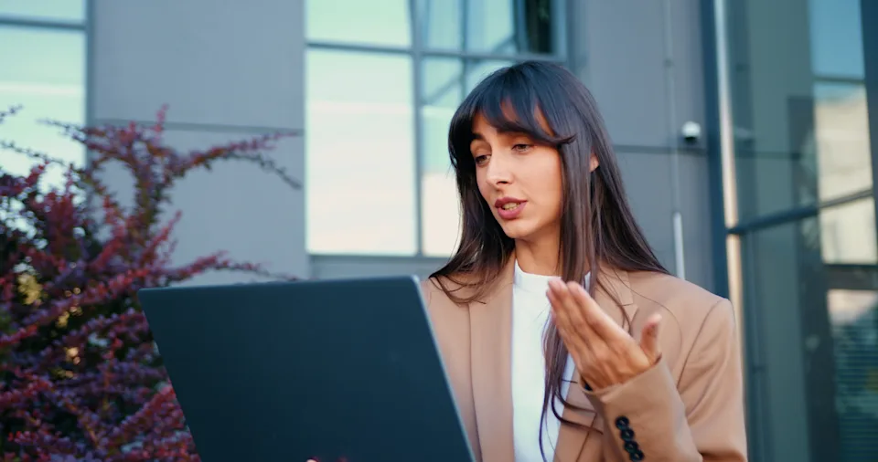 Young businesswoman looking at her laptop screen, responding to messages and engaging in a virtual meeting.