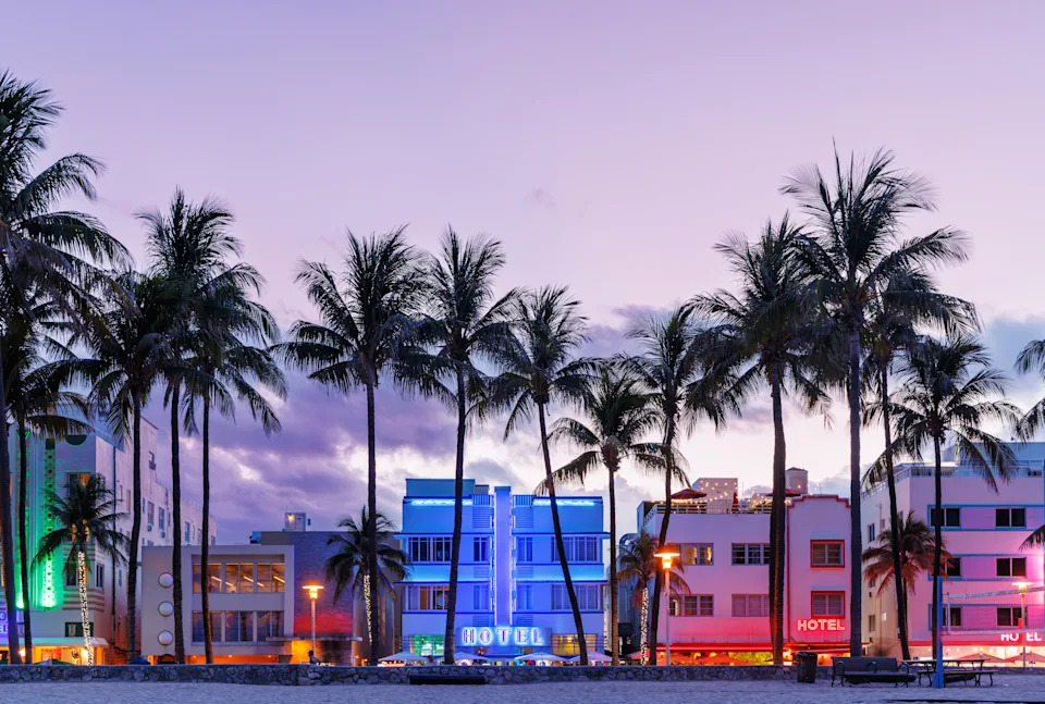 Colorful Art Deco hotels on Ocean Drive in Miami Beach glow under the warm hues of a vibrant sunset, capturing the lively charm of South Beach