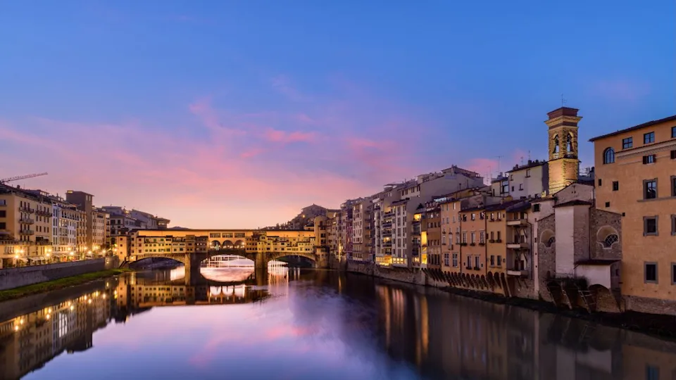 Florence, Italy at the Ponte Vecchio Bridge crossing the Arno River at twilight.