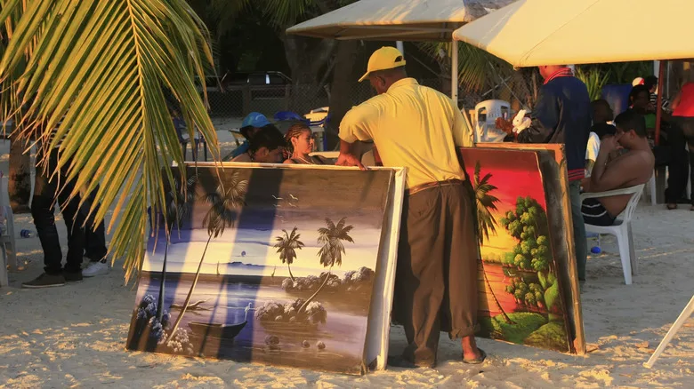 A man selling paintings on the beach in the Caribbean.