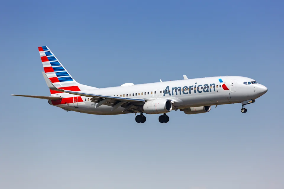 An American Airlines plane flies across a blue sky