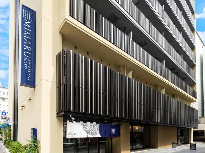 Street view of the Mimaru Apartment Hotel, a modern multi-story building with a sign displaying its name