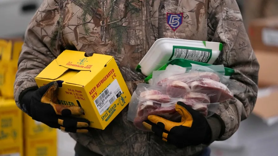 FILE – A Utah Food Bank volunteer carries groceries for the needy at a mobile food pantry distribution site Dec. 21, 2022, in Salt Lake City. (AP Photo/Rick Bowmer, File)