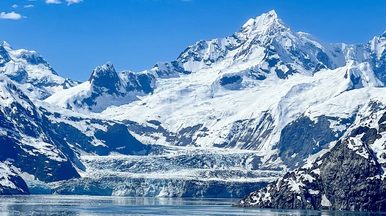 Snow cascades down to bay in Glacier Bay National Park, Alaska