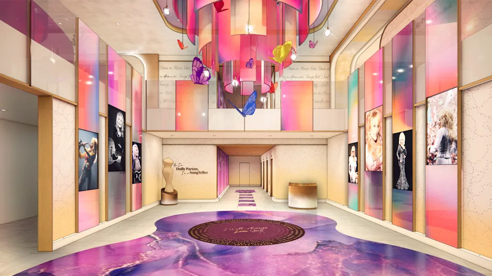 A lobby with pink and purple, Dolly photos on the walls, a giant guitar on the floor, and a butterflies chandelier