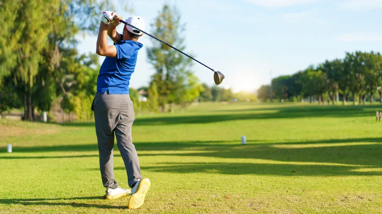 Golfer taking a swing at a course on a sunny day
