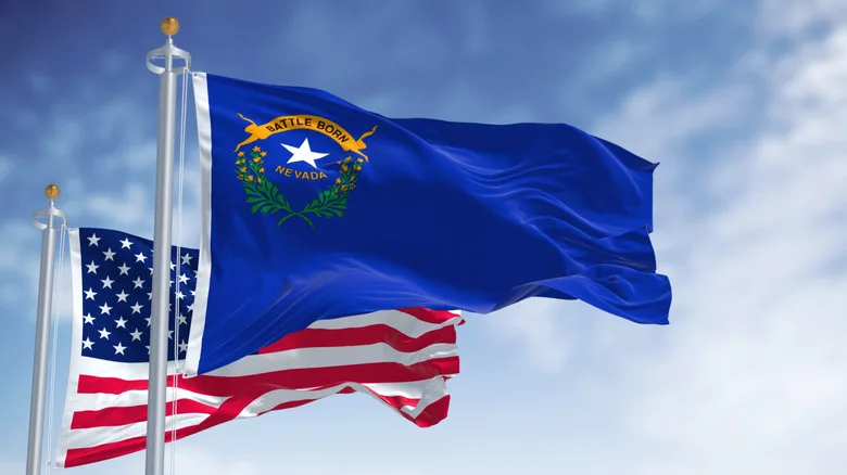 The state flag of Nevada waving in the wind with the U.S. flag in the background