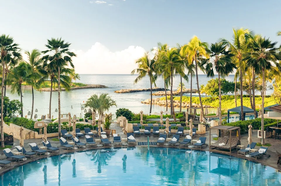 Four Seasons Resort Oahu at Ko Olina Lounge chairs lay around the resorts main pool.