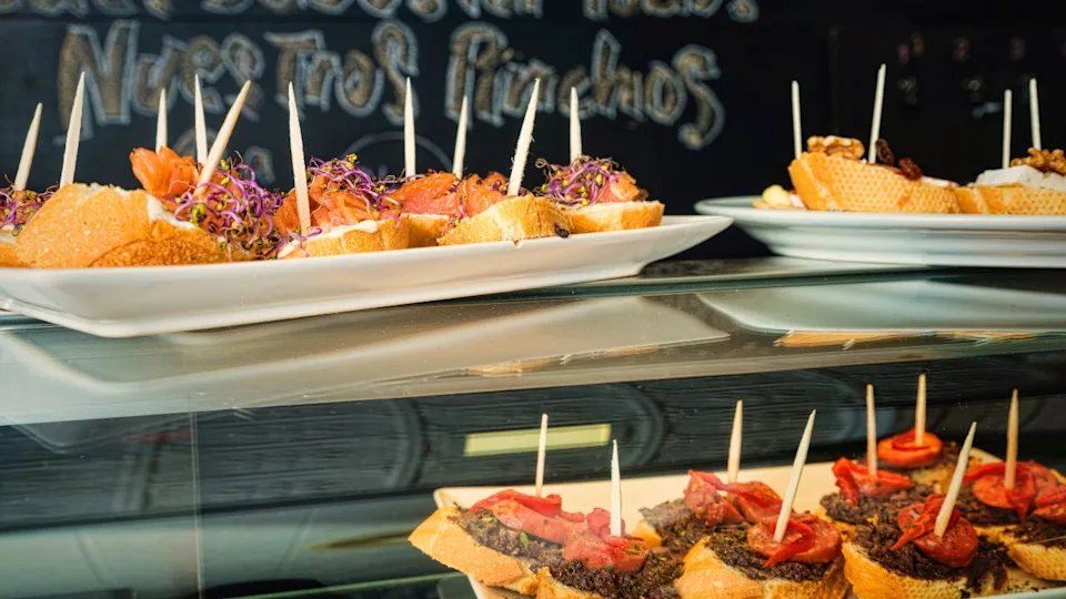 Tapas bar counter with assorted pincho tapas and a traditional chalboard in the background