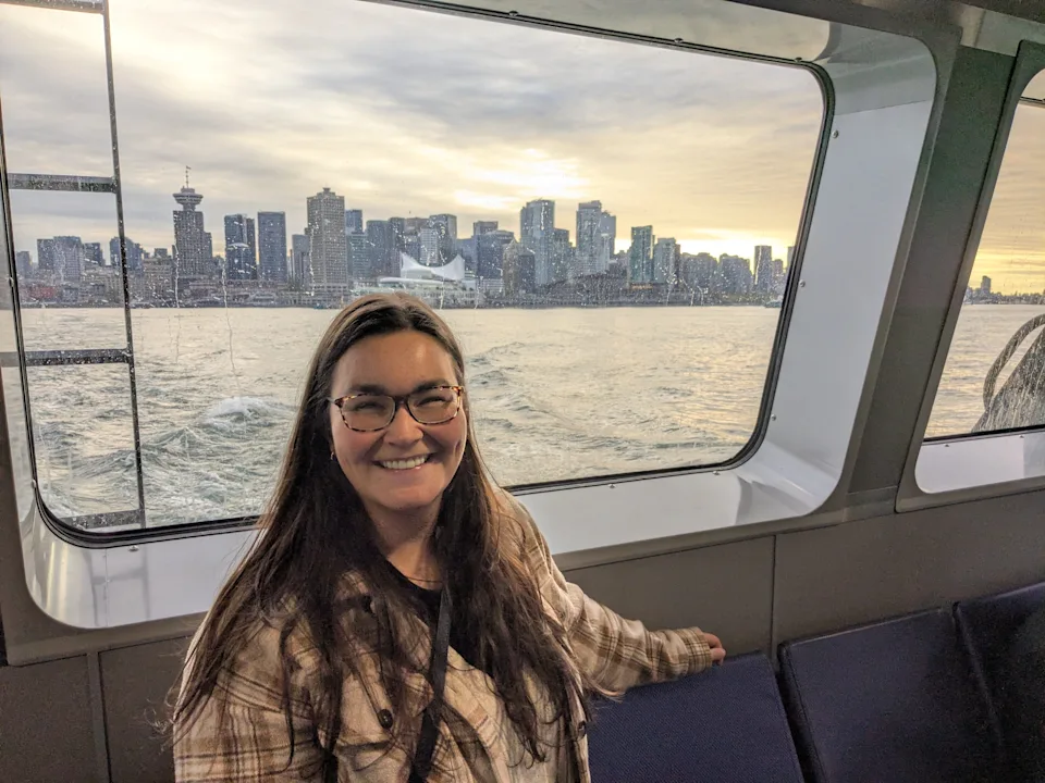 The author posing on a SeaBus with the skyline of Vancouver in the background.