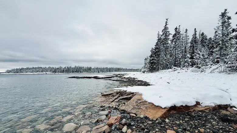 Water laps snowy banks in Acadia National Park, Maine