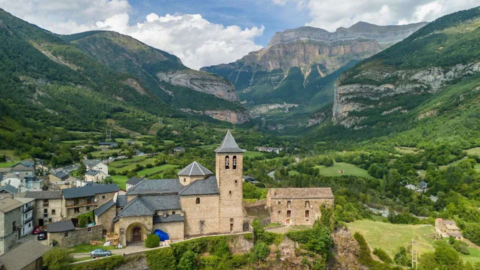 Aerial view of the Torla-Ordesa village and Ordesa-Monte Perdido National Park in the Spanish Pyrenees mountains. Medieval buildings and the Church of San Salvador in Torla-Ordesa, Huesca, Spain.