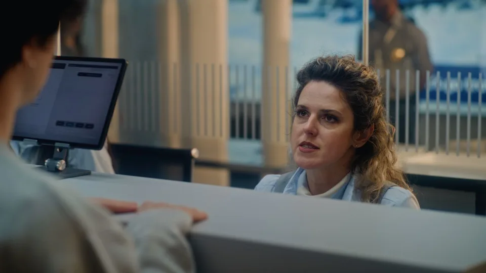 Airport Check-in Counter: Female Airline Check-in Attendant Talking to Passenger, Asking Questions During Passport Check for Boarding Flight. Security Checkpoint in International Airport Terminal.