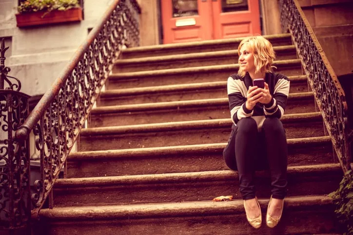 Young woman sitting on stairs outside her West Village apartment.