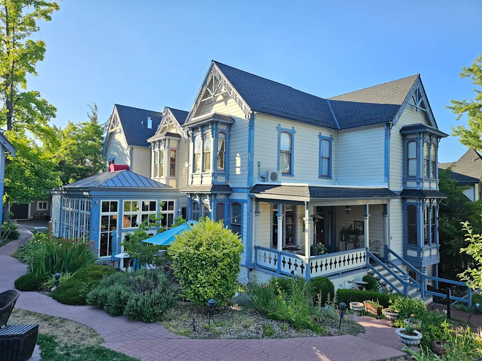 A Victorian home with yellow paint and blue trim