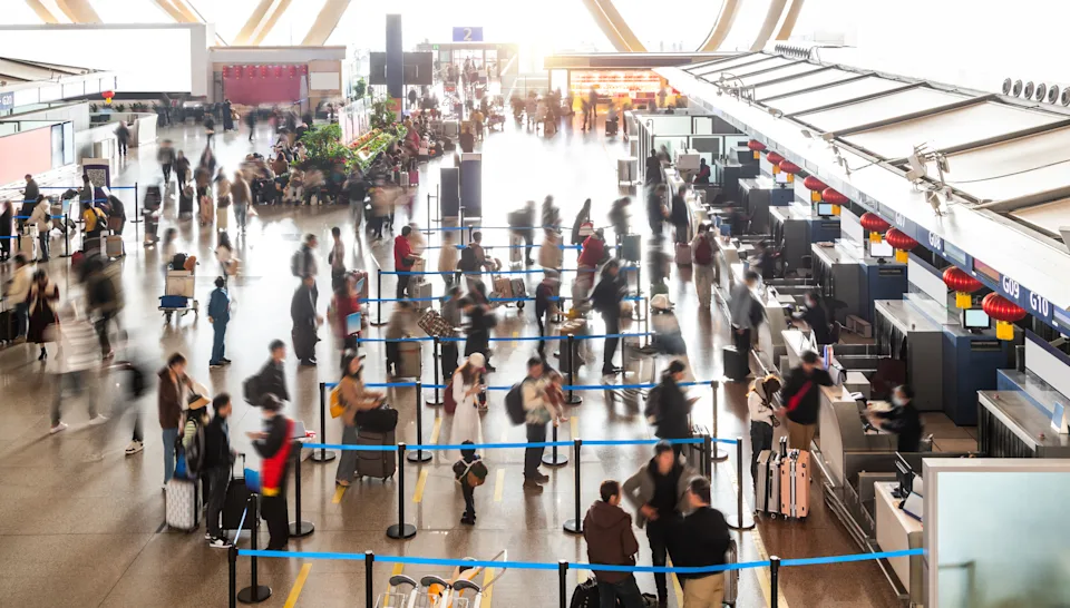 Crowded commuter people with luggage in airport waiting for check-in
