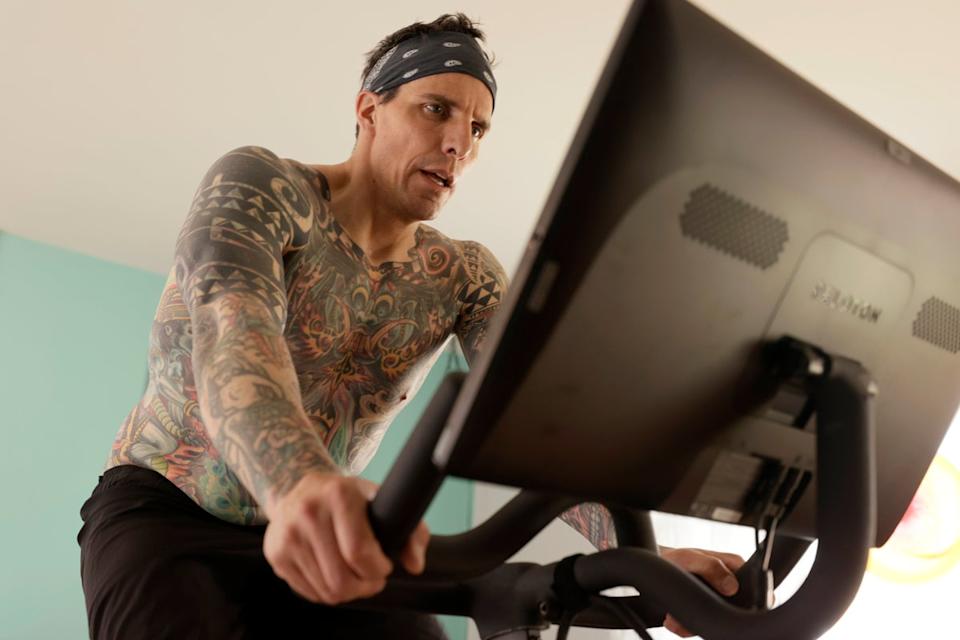 A man works out on a Peloton exercise bike at home. Many people swear by home gym systems like these bikes (Getty Images)