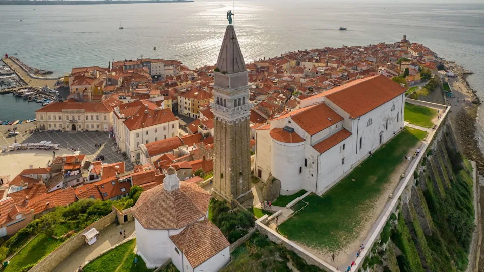 Aerial view of Piran old town, Slovenia, featuring a historic lighthouse and turquoise sea. A picturesque Mediterranean coastal gem with rich history and stunning scenery
