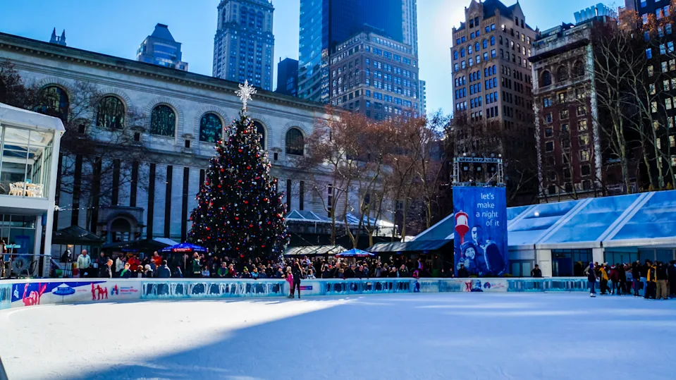 New York City, USA, December 27, 2014, People enjoying ice skating on famous ice rink in bryant park surrounded by skyscrapers of downtown after christmas