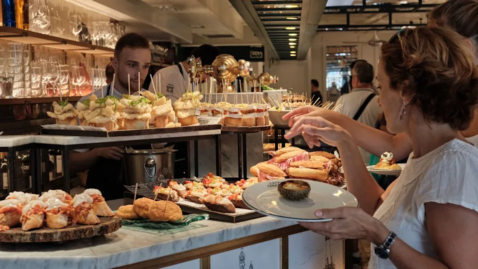SAN SEBASTIAN, SPAIN - JULY 17: Tourists watch and eat the pintxos from the bar of a bar in San Sebastian, Basque Country Spain July 17, 2019 in San Sebastian, Spain.