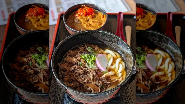 A bowl of udon and a small bowl of curry on a counter inside Don Udon