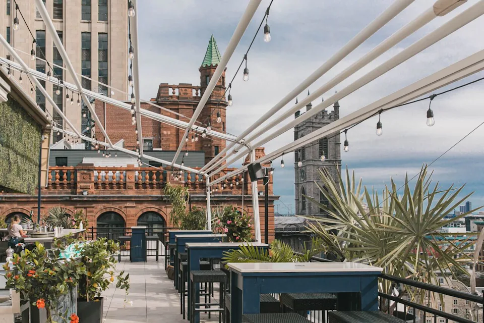 View from the patio of Hotel Place d’Armes with fairy lights hung on a trellis and a view of the city in the background. - Courtesy of Hotel Place d'Armes