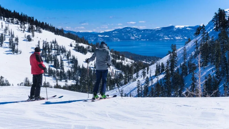 Two middle aged men on skis look out over the lake tahoe mountains, USA