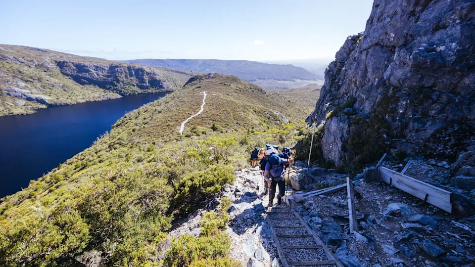 Hiker climbing on the Overland Track from near Marions Lookout with a view over Crater Lake on a warm autumn morning in Cradle Mountain, Tasmania, Australia
