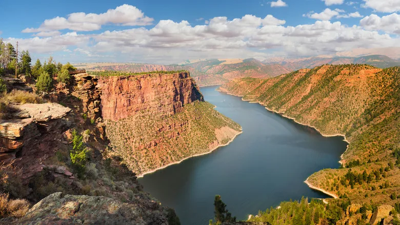 The Flaming Gorge National Recreation Area with a wide river and red dramatic cliffs and hills around it