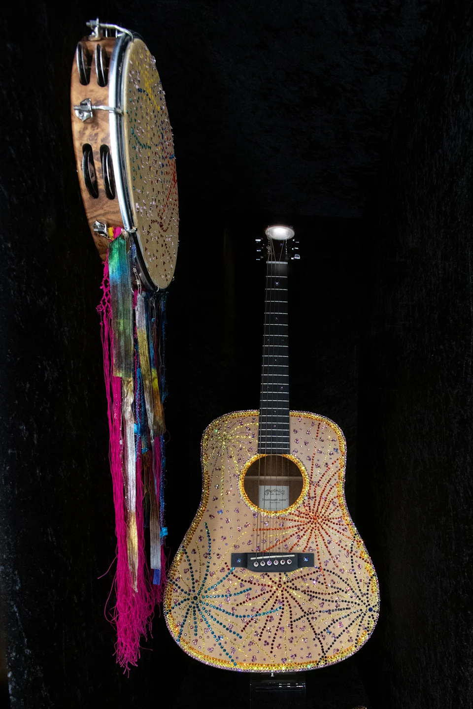 A bedazzled guitar and a tambourine with streaming ribbons