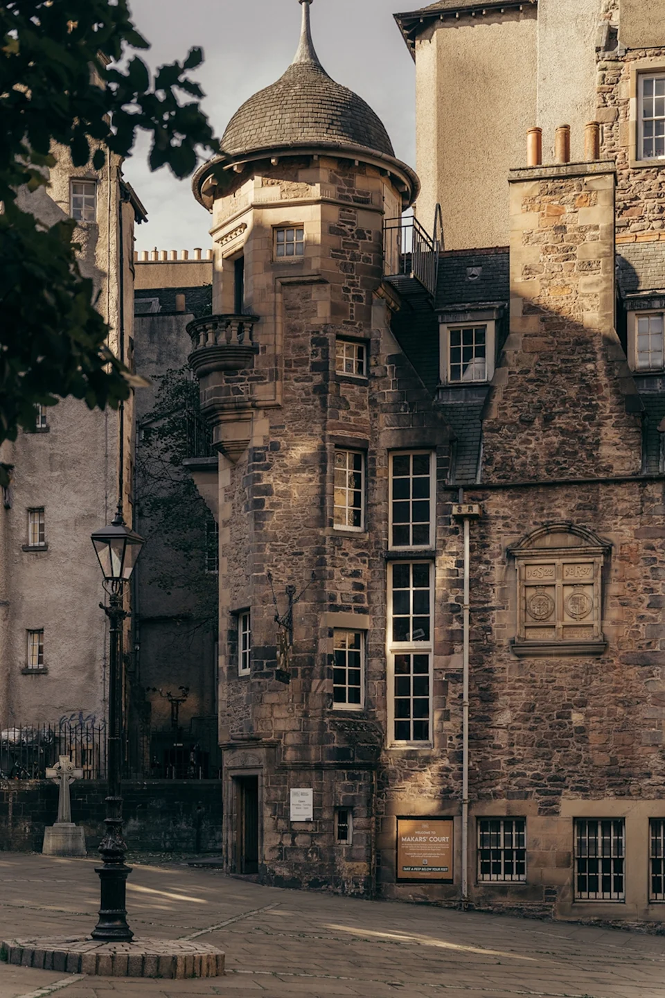 The gloomy and mysterious exteriors of a stone building with tall wooden windows and a small tower on the corner.