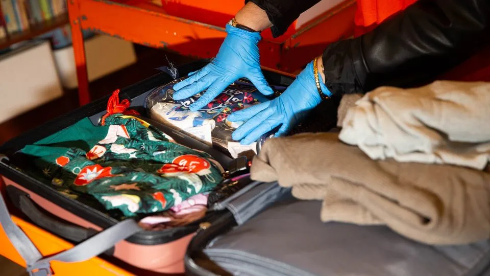 Sonni Hood, senior manager of communications at Unclaimed Baggage, shows how items in lost suitcases are inspected and divided into different categories. - Austin Steele/CNN