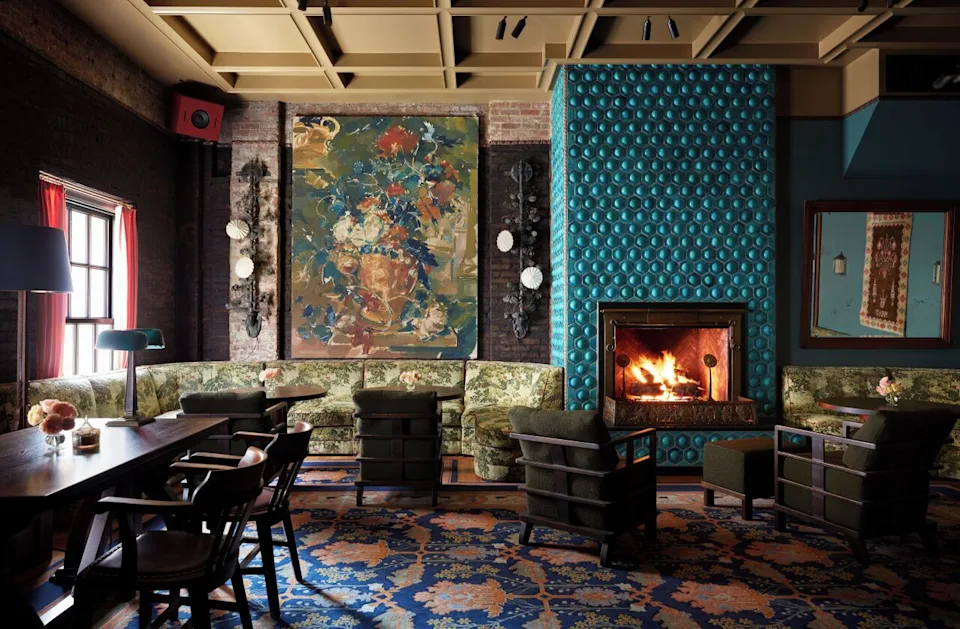 View of lobby of the Nine Orchard Hotel featuring richly-colored tapestries and walls with bold accents, dark mahogany furniture and a blazing fire. - Courtesy of the Nine Orchard Hotel