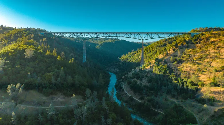 The tall ironwork Foresthill Bridge spans the American River amongst forest covered canyons