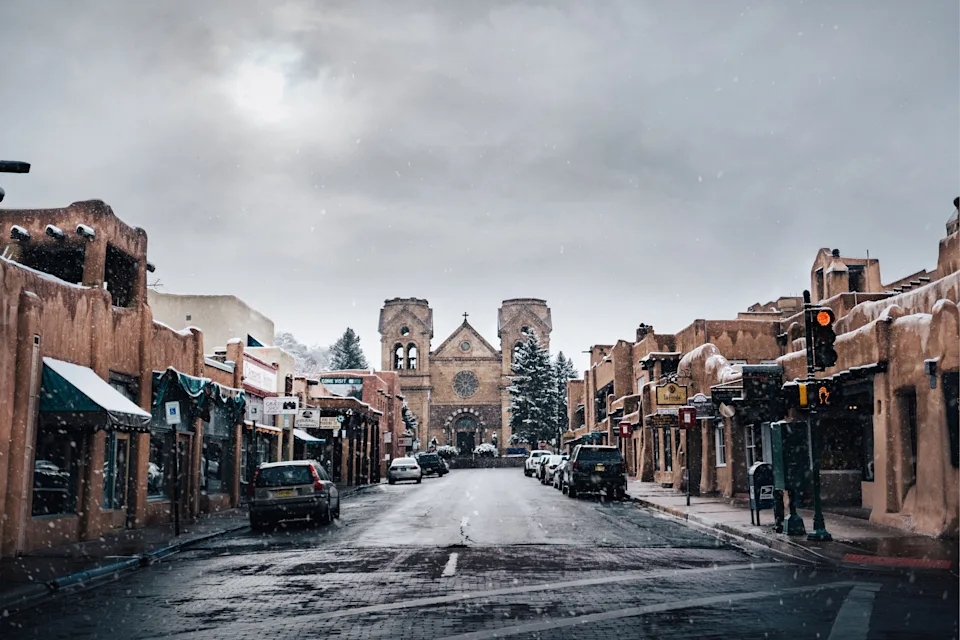 Adobe buildings line a street ending at the Cathedral Basilica of St. Francis of Assisi