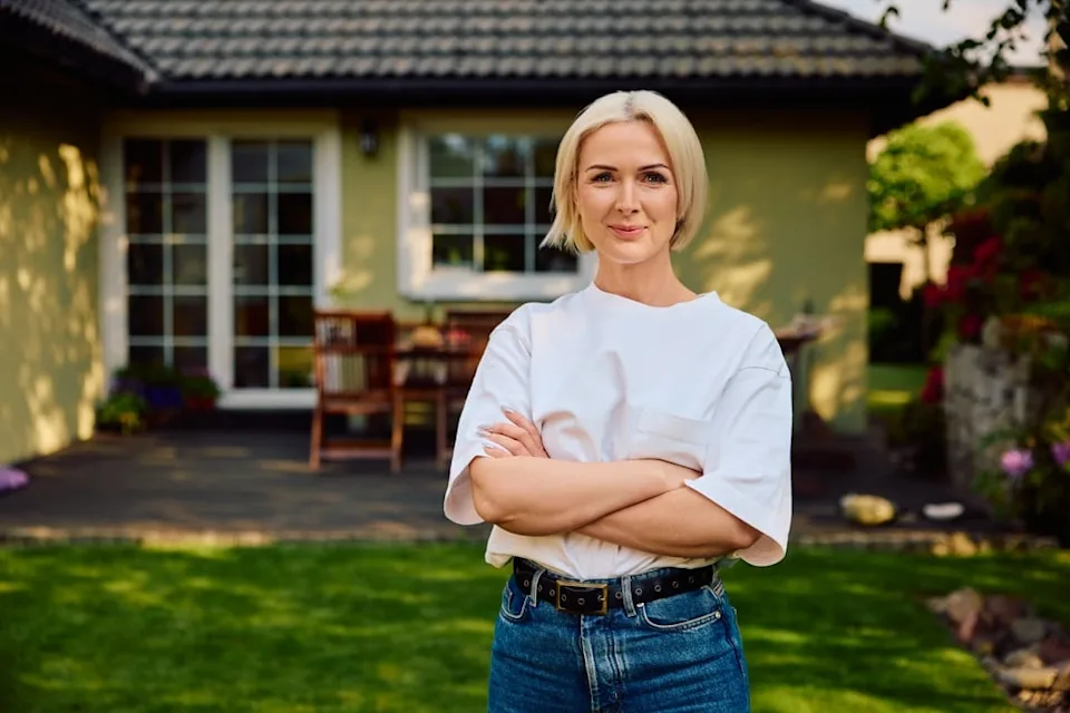 Woman standing outside her home looking confident.