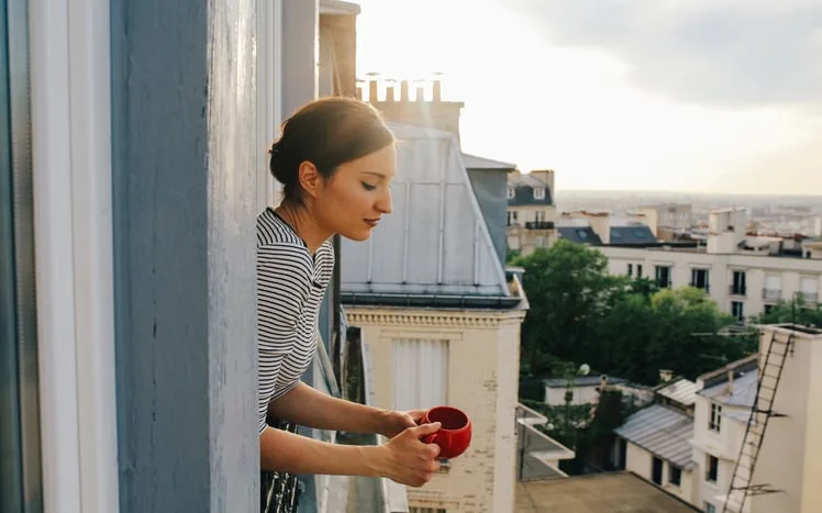 Woman drinking coffee on the balcony apartment in Montmartre, Paris. 