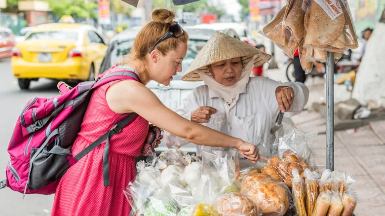 Western woman buying street food from Vietnamese vendor