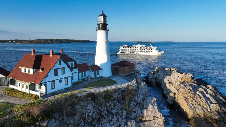 A historic lighthouse in the U.S., with one of American Cruise Lines' Patriot-class ships in the background
