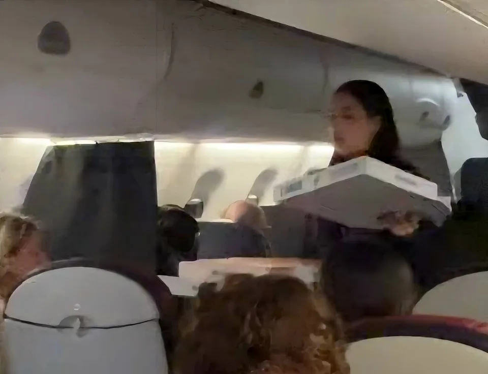 A flight attendant passes out pizza to the hungry passengers 