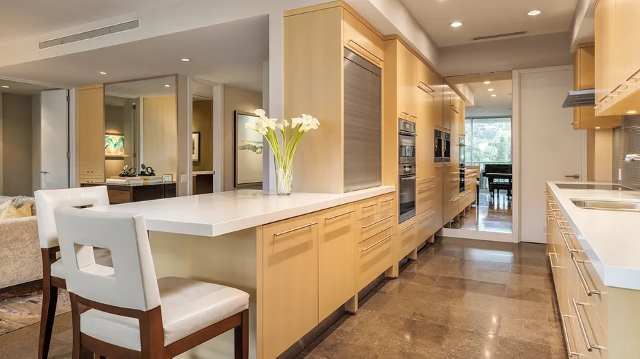 The galley kitchen features an eat-in island and wooden cabinets.