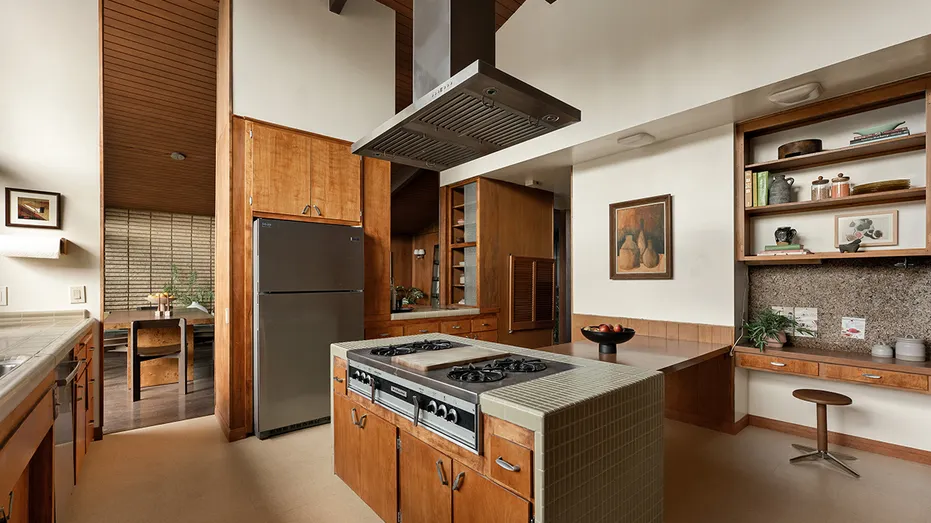 The kitchen features an eat-in center island, built-in shelves and views of the backyard.