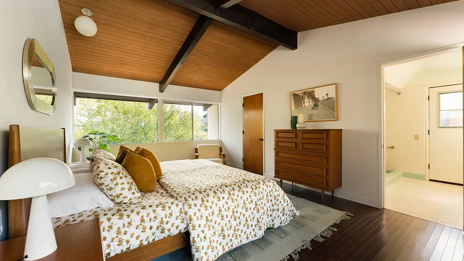 The primary bedroom features a big window with views of the surrounding greenery.