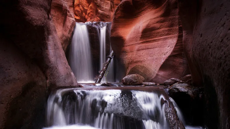 Waterfall inside slot canyon with ladder leading up in Kanarra Falls
