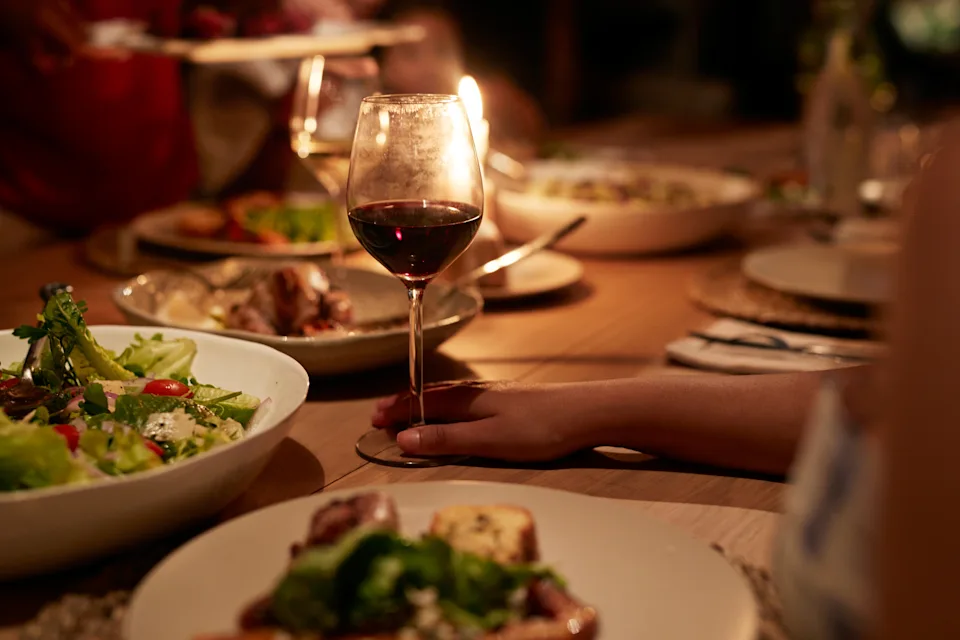 A candlelit dinner table with wine, salads, and various dishes, suggesting a cozy dining experience possibly in a travel context