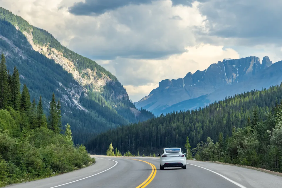 Car driving along Icefields Parkway toward towering Rocky Mountains