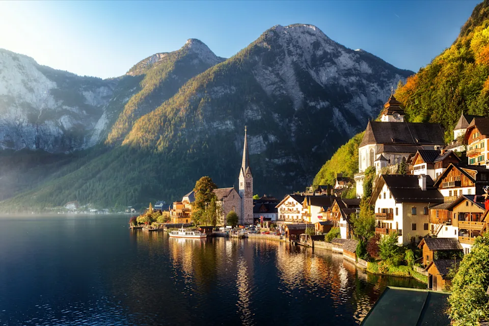 Scenic lakeside view of Hallstatt, Austria, showing traditional alpine houses, a church with a tall spire, and mountains in the background