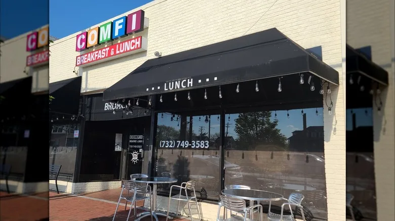 The exterior of Comfi with metal tables outside under a black awning